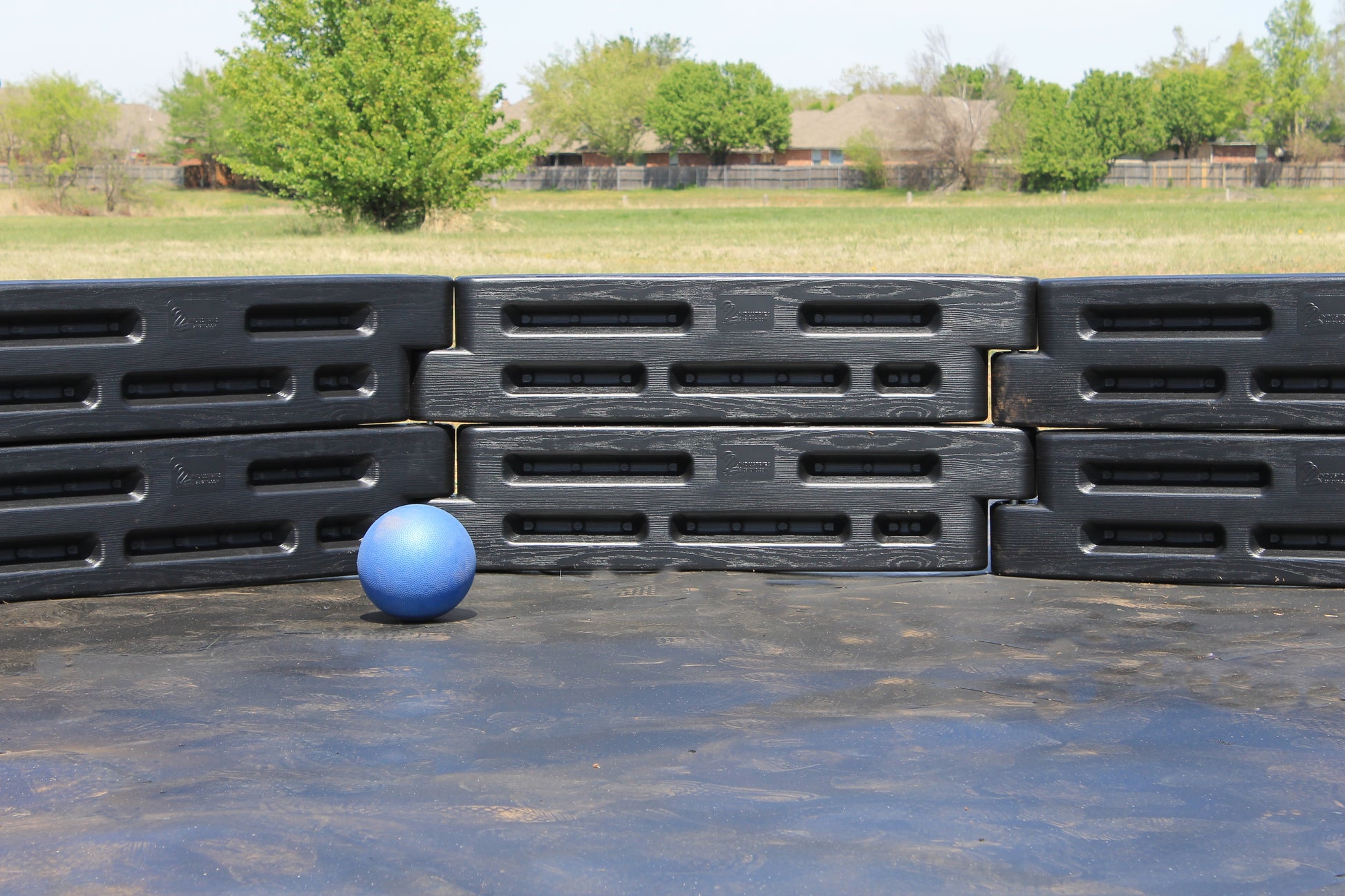Close-up of a blue gaga ball inside a black modular gaga pit on an outdoor play surface by Castle Sports.