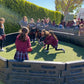 Students playing gaga ball inside a black modular gaga pit on turf at a school playground, featuring Castle Sports equipment.